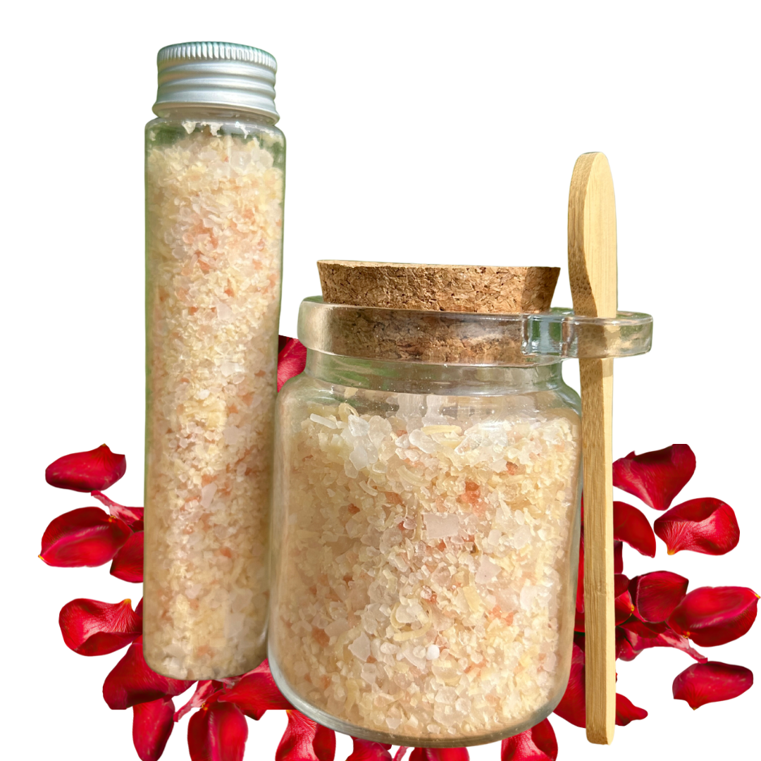 Two containers with bath salts and a wooden spoon on a white background with red flowers.