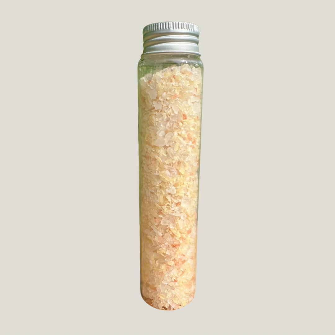 Glass bottle filled with a light-colored salt, magnesium, and shredded soap on a gray background