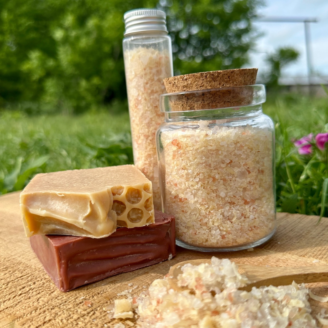 Bar of soap and jars with natural products on a wooden surface outdoors.
